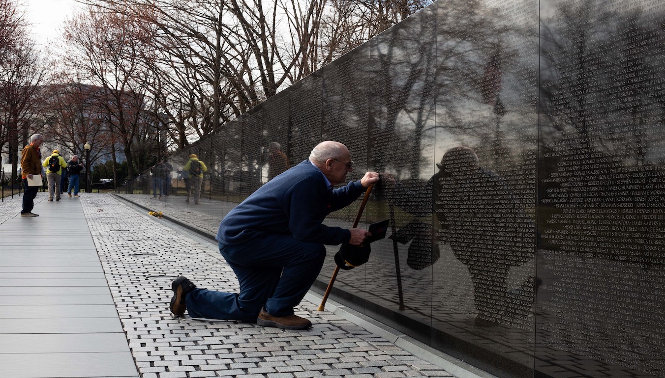 Veteran kneeling at Vietnam war memorial