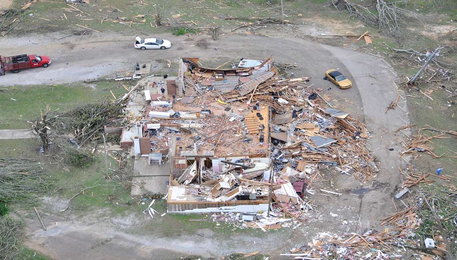 homes destroyed by the California tornado and cars around the debris.