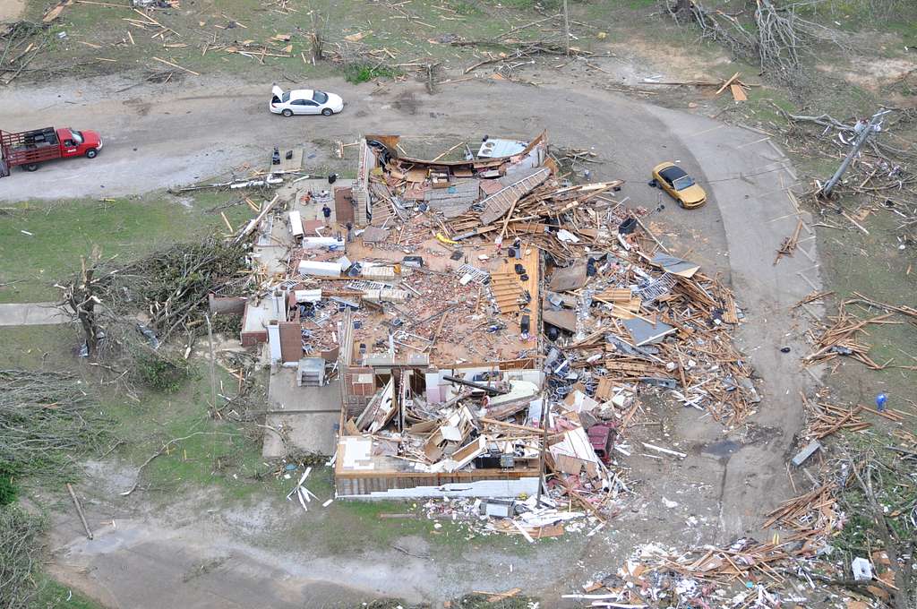 Homes destroyed by natural a disaster and 3 vehicles around the destroyed houses.