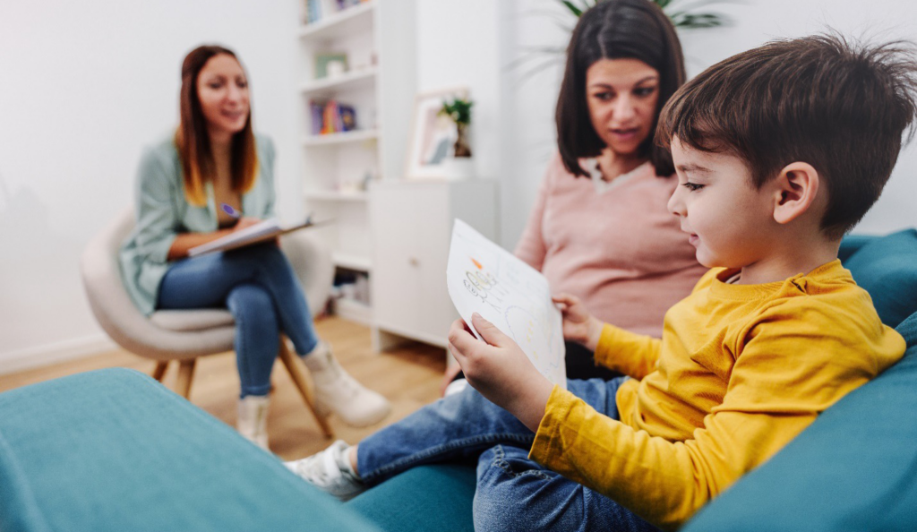 A child engaging in therapy with his mother and a therapist.