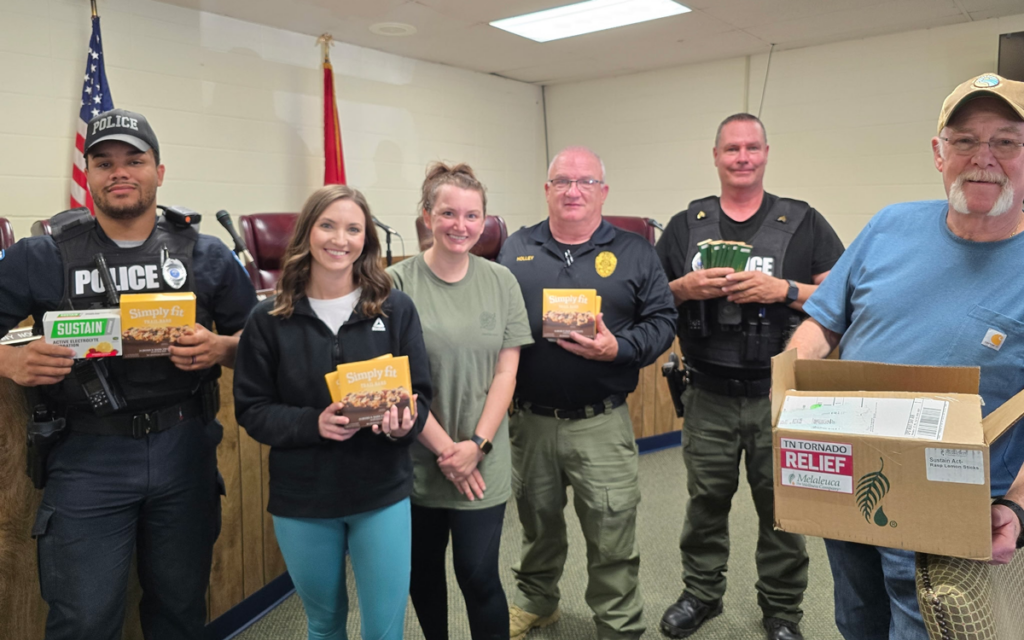 Police officers and employees holding Melaleuca products.