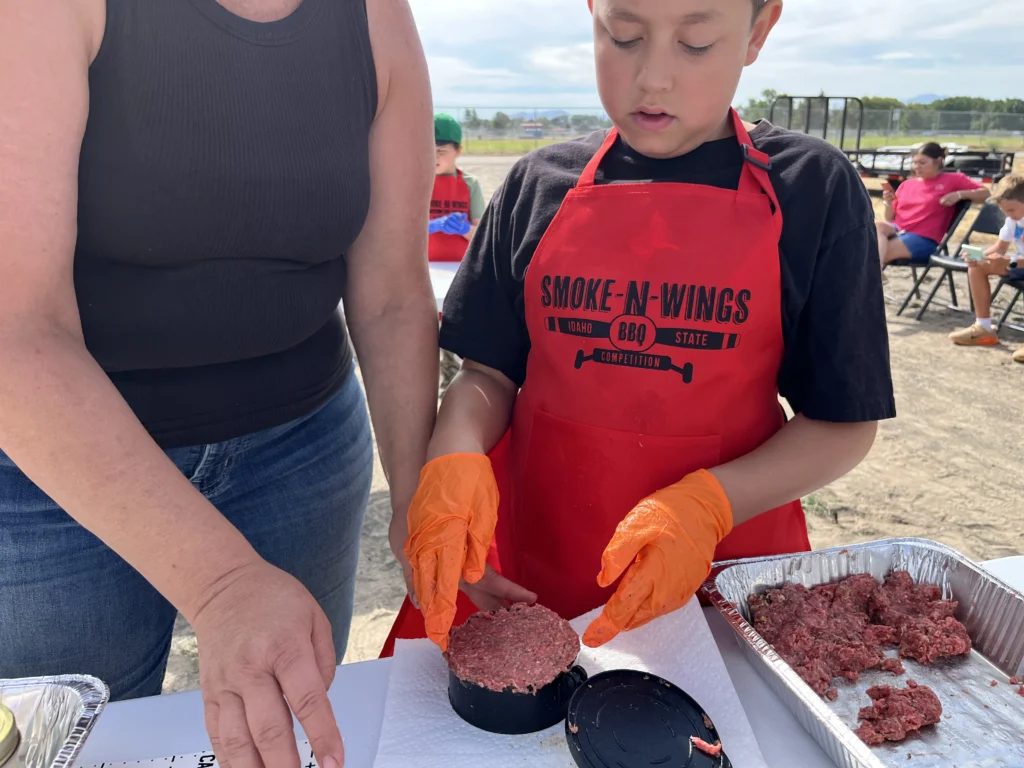 Small hands, big burgers and plenty of imagination were on display at the Smoke-N-Wings Kids-Q competition.
Riverbend Ranch sponsored both divisions of the Smoke-N-Wings Kids-Q competition in June 2026 by providing the high-quality ground beef used by the young competitors. The donation gave each child the same starting point and plenty of room to use their imagination, test new flavors and enjoy a little friendly competition.
Riverbend Ranch, a division of Melaleuca founded by Frank and Belinda VanderSloot, has spent more than 30 years raising premium Black Angus cattle with an emphasis on quality, responsible care and American ranching traditions. The Kids-Q took place alongside a Kansas City Barbeque Society-sanctioned professional competition that drew teams from across the United States and Canada, giving the children an up-close look at the world of competitive barbecue.
Each young griller started with the same key ingredient: Riverbend Ranch ground beef. What happened next was entirely their own.
With a parent or family member nearby to help when needed, the children shaped patties, mixed seasonings and planned burgers that reflected their individual tastes. The competition’s flexible, age-appropriate rules allowed the young cooks to learn by doing while still keeping the experience safe, encouraging and fun. 

A Recipe for Family Fun